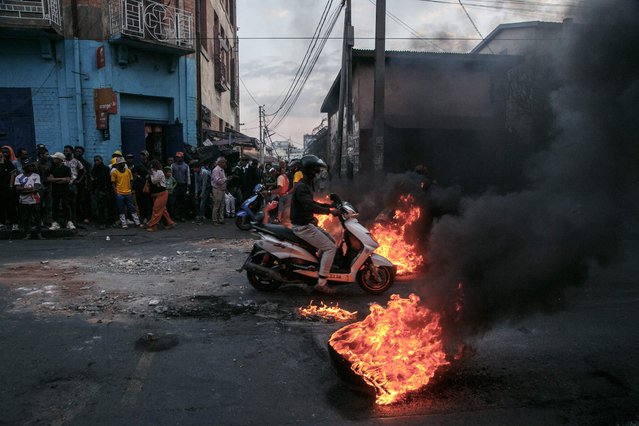 A motorcyclist drives past barricades set up by protesters as they demonstrate against repeated water and electricity outages in Antananarivo on September 25, 2025. A heavy police presence patrolled the capital from early morning after authorities banned the demonstration the day before. But the protesters defied the order and tried to break through a police barricade to reach their planned meeting point in the Ambohijatovo district in central Antananarivo. (Photo by RIJASOLO/AFP Photo)