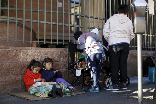 Children sit on a piece of cardboard as they wait in line for an early Thanksgiving meal served to the homeless at the Los Angeles Mission in Los Angeles, California, November 25, 2015.   REUTERS/Mario Anzuoni