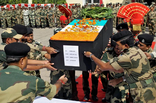 Indian Border Security Force (BSF) officers place the coffin of their fallen colleague, who died after shelling across the border between India and Pakistan, during a wreath laying ceremony at their headquarters on the outskirts of Jammu October 24, 2016. (Photo by Mukesh Gupta/Reuters)