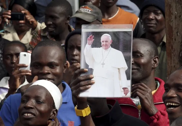 A faithful holds a Pope Francis picture at the Kangemi slums on the outskirt of Kenya's capital Nairobi, November 27, 2015. (Photo by Stefano Rellandini/Reuters)