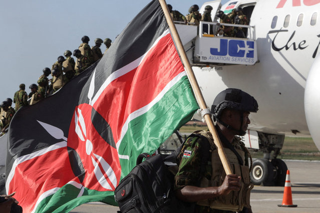 A Kenyan police officer carries a Kenyan flag after disembarking in Haiti to join an expanded multinational force with a mandate to fight gangs, at Toussaint Louverture International Airport, in Port-au-Prince, Haiti on December 8, 2025. (Photo by Jean Feguens Regala/Reuters)