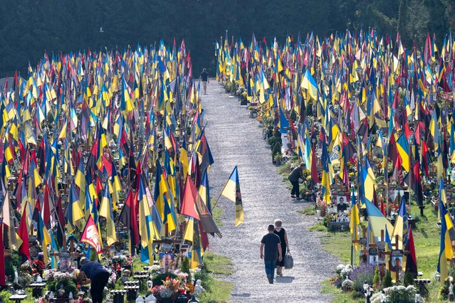 People walk among graves at the Field of Mars cemetery in Lviv on August 24, 2024 to commemorate the fallen soldiers on the occasion of the Independence Day Of Ukraine, amid the Russian invasion of Ukraine. (Photo by Ivan Stanislavsky/AFP Photo)