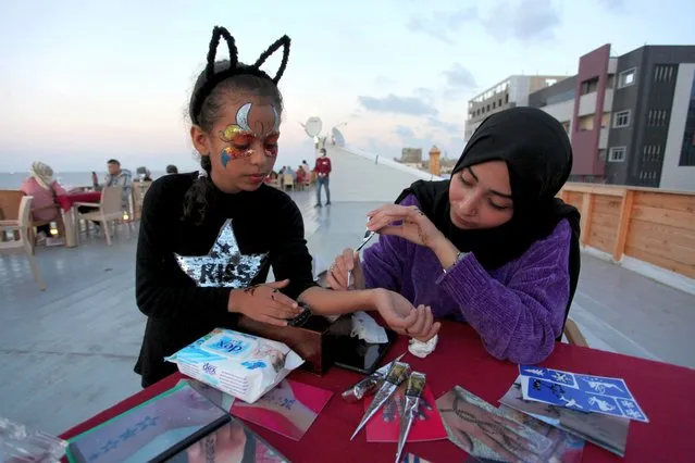 Palestinian artist Nour Abu Hada, applies henneh herbal tattoo indicating 2021 on the hand of a girl, in a cafe on the beach of Gaza City on December 24, 2020. Henna is a dye prepared from the plant Lawsonia inermis, also known as the henna tree, the mignonette tree, henna has been used since antiquity in ancient Egypt and the Kingdom of Kush to dye skin, hair and fingernails, as well as fabrics including silk, wool and leather. (Photo by APA Images/Rex Features/Shutterstock)