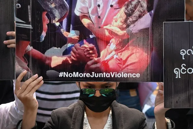 A protester holds up a poster with a portrait of Mya Thwate Thwate Khaing who died from a gunshot wound after being shot in the head last week, during a demonstration against the military coup in Yangon on February 19, 2021. (Photo by Sai Aung Main/AFP Photo)