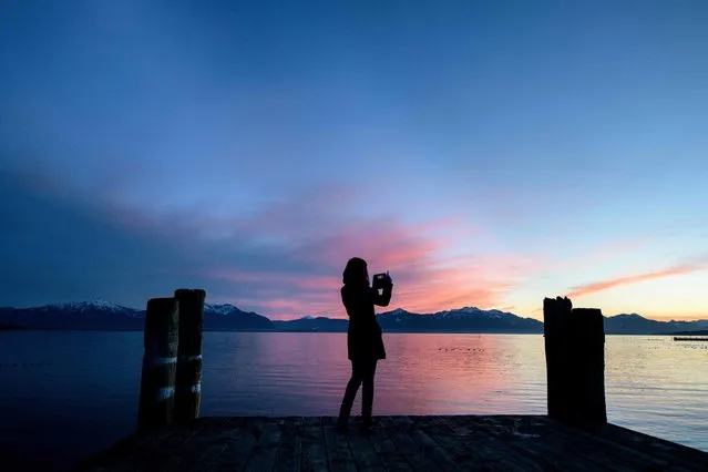 A youth takes pictures of the sunset with her mobile phone on January 1, 2018 on a pier over the Chiemsee lake in the Bavarian village of Seebruck, southern Germany. (Photo by Matthias Balk/AFP Photo/DPA)