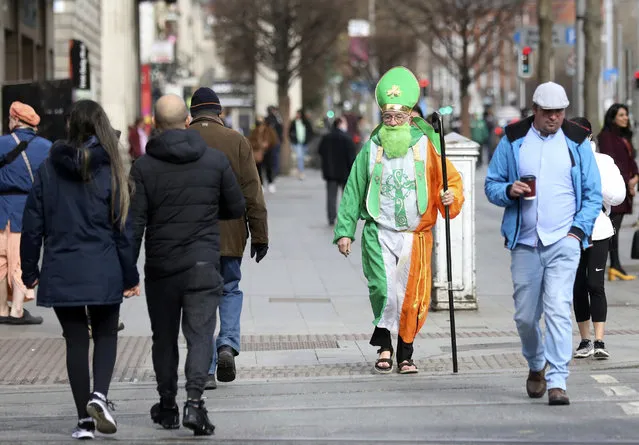 A man dressed as St Patrick walks down O'Connell street in Dublin, Ireland, Wednesday, March, 17, 2021. The St Patrick's Day parades across Ireland were canceled for the second year due to COVID-19 pandemic. (Photo by Peter Morrison/AP Photo)