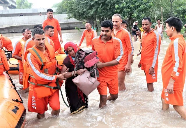 National Disaster Response Force (NDRF) personnel rescue local people from a flooded area in low-lying area of Yamuna river in New Delhi, India, 13 July 2023. The Yamuna river is flowing above the danger mark in Delhi and the government has issued warnings over flood-like situations and asked people living on the river bed or living in low-lying areas to evacuate their homes. (Photo by Harish Tyagi/EPA/EFE/Rex Features/Shutterstock)