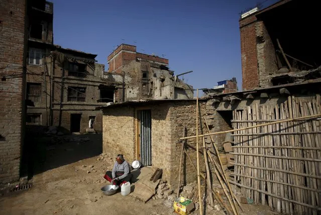 A woman washes cloths as she sits outside her temporary shelter built near the houses damaged during an earthquake earlier this year, in Bhaktapur, Nepal December 28, 2015. (Photo by Navesh Chitrakar/Reuters)