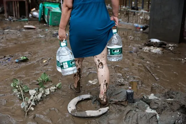 A resident holding bottles of water as she walks back to a residential compound, after remnants of Typhoon Doksuri brought rains and floods in Beijing, China on August 2, 2023. (Photo by Tingshu Wang/Reuters)