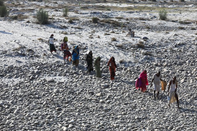 Devotees cross the dry riverbed of the Ganges river during Kumbh Mela, or the Pitcher Festival, amid the spread of the coronavirus disease (COVID-19), in Haridwar, India, April 13, 2021. (Photo by Anushree Fadnavis/Reuters)