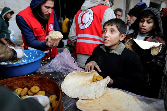 Syrians evacuated from eastern Aleppo, get food aid from the Syrian Red Crescent inside a shelter in government controlled Jibreen area in Aleppo, Syria November 30, 2016. (Photo by Omar Sanadiki/Reuters)