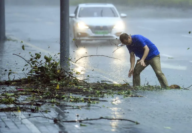 In this photo released by Xinhua News Agency, a man removes debris blocking a drain on a road at Nanshan District in Shenzhen in south China's Guangdong Province, Sunday September 16, 2018. Typhoon Mangkhut barrelled into southern China on Sunday after lashing the northern Philippines with strong winds and heavy rain that left at least 64 people dead and dozens more feared buried in a landslide. (Photo by Mao Siqian/Xinhua via AP Photo)