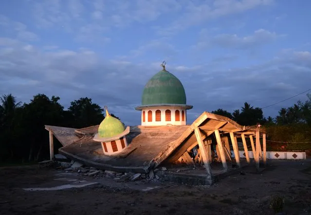 A collapsed mosque is seen as the sun set at Kayangan subdistrict in North Lombok on West Nusa Tenggara province on August 8, 2018, three days after an earthquake hit the area. More than 70,000 people left homeless by a deadly earthquake on the Indonesian island of Lombok are sleeping in makeshift shelters and lack food, medicine and clean water, officials said on August 8. (Photo by Sonny Tumbelaka/AFP Photo)