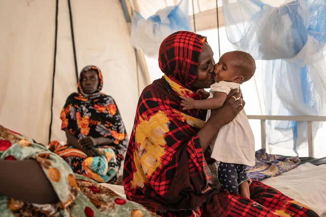 Jamia Ishak Osman, 35, kisses her child who is suffering from malaria at the malaria department tent in the Doctors Without Borders clinic inside the Adre camp, where around 200,000 people are currently taking refuge on September 19, 2023 in Adre, Chad. The conflict in Sudan, entering its sixth month, has left thousands of civilians dead and displaced more than five million people. More than 420,000 people have already found refuge in neighbouring Chad as hundreds continue to arrive daily. (Photo by Abdulmonam Eassa/Getty Images)