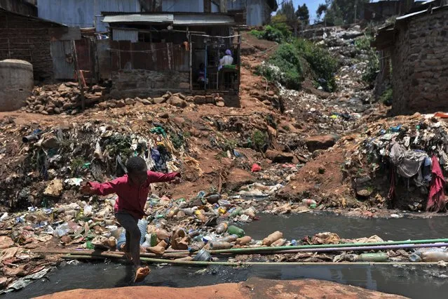 A young resident of Nairobi's Kibera slum, one of Africa's largest slums, crosses a heavily polluted section of the Ngong river on September 19, 2018. (Photo by Tony Karumba/AFP Photo)