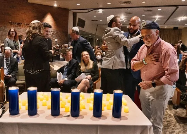 Men embrace and pray after placing candles on a small table during a “Vigil for Israel”, at the Stephen Wise Temple in Los Angeles, Sunday, October 8, 2023, to pray, sing and honor the memory of those killed in the recent attack in Israel, and to pray for peace and the safe return of people kidnapped. (Photo by Richard Vogel/AP Photo)