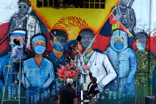 Street artists paint a mural depicting Covid-19 coronavirus frontline workers in Kathmandu on June 10, 2021. (Photo by Prakash Mathema/AFP Photo)