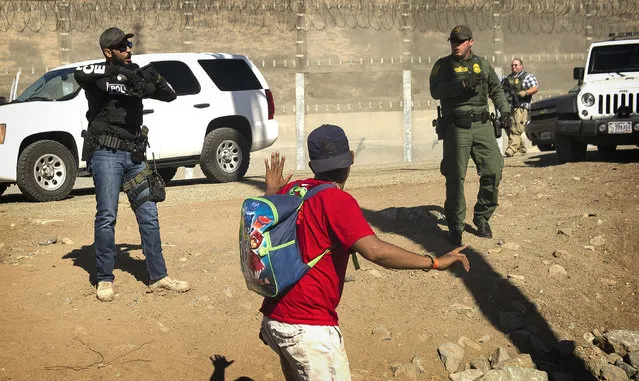 A Central American migrant is stopped by U.S. agents who order him to go back to the Mexican side of the border, after a group of migrants got past Mexican police at the Chaparral crossing in Tijuana, Mexico, Sunday, November 25, 2018, at the border with San Ysidro, California. The mayor of Tijuana has declared a humanitarian crisis in his border city and says that he has asked the United Nations for aid to deal with the approximately 5,000 Central American migrants who have arrived in the city. (Photo by Pedro Acosta/AP Photo)