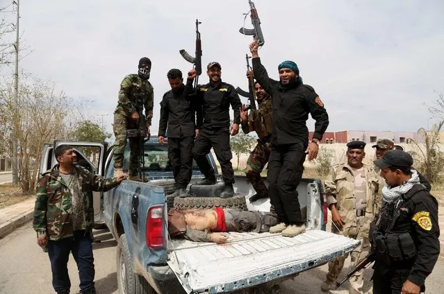 Shiite militiamen chant slogans as they take the body of an Islamic State fighter for burial after overnight clashes in Tikrit, 130 kilometers (80 miles) north of Baghdad, Iraq, Tuesday, March 24, 2015. (Photo by Khalid Mohammed/AP Photo)