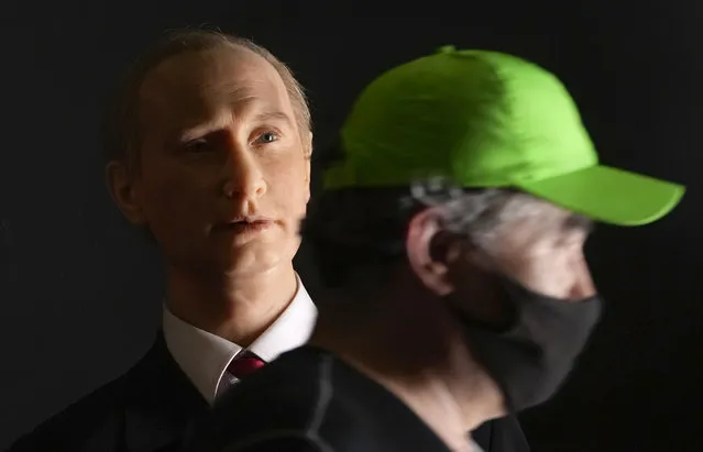 A man wearing a face mask to protect against coronavirus infection walks past a wax figure depicting Russian President Vladimir Putin displayed at a wax sculptures exhibition in St. Petersburg, Russia, Wednesday, June 30, 2021. Speaking in a live call-in show Wednesday, Putin said that decisions by local authorities in a number of regions who made vaccination mandatory for some workers should help contain the new wave of infections and avoid a lockdown. (Photo by Dmitri Lovetsky/AP Photo)