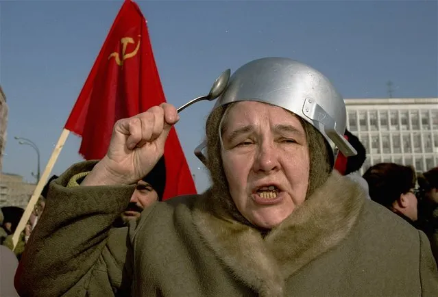 In this file photo taken on Monday, March 8, 1993, an old communist with a saucepan on her head strikes it with a spoon while shouting out anti-Yeltsin slogans under the former Soviet flag during a pro-communist women's protest march called “empty pots” in downtown Moscow. When Alexander Zemlianichenko started working as an AP photographer in Moscow, the Soviet Union was nearing its demise. (Photo by Alexander Zemlianichenko/AP Photo)