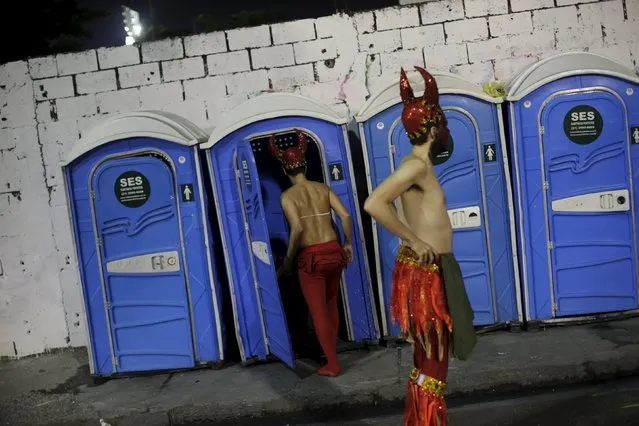 A reveller enters a portable bathroom as a fellow reveller stands near outside the Sambadrome during the carnival parade in Rio de Janeiro February 8, 2016. (Photo by Ricardo Moraes/Reuters)