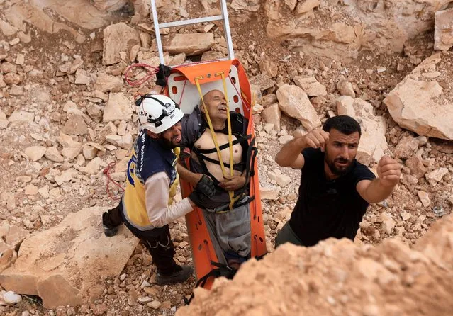Members of the Syrian civil defence, known as the White Helmets, evacuate a wounded man from the site after a landmine reportedly exploded under the bus transporting them east of the opposition-held city of Al-Bab in the northern Aleppo province, on September 23, 2022. (Photo by Bakr Alkasem/AFP Photo)