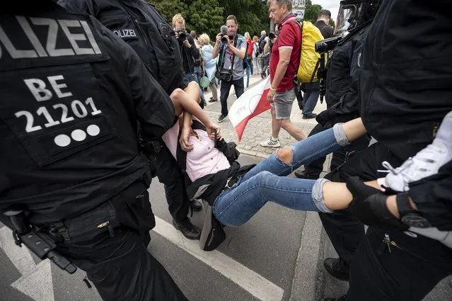 Police arrest a demonstrator at an unannounced demonstration at the Victory Column, in Berlin, Sunday August 1, 2021, during a protest against coronavirus restrictions. (Photo by Fabian Sommer/dpa via AP Photo)