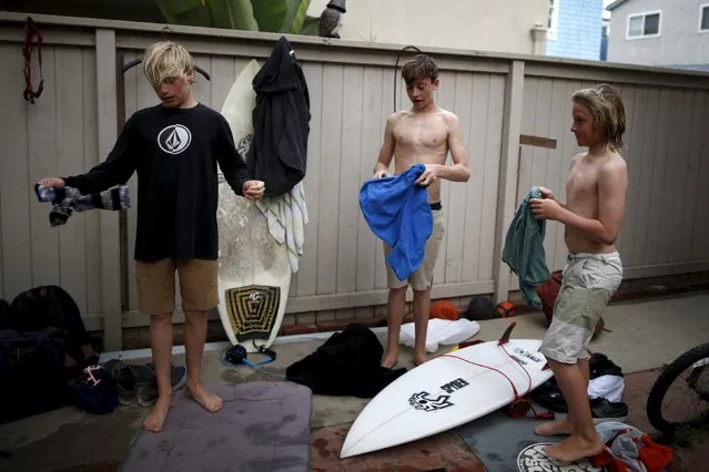 (L-R) Carlos Price Gracida, 13, Luke Personius, 12, and Shane Moseley, 13, change for school in their friend Kieran Walls' (not shown) yard after surfing at sunrise in Hermosa Beach, California March 31, 2015. (Photo by Lucy Nicholson/Reuters)