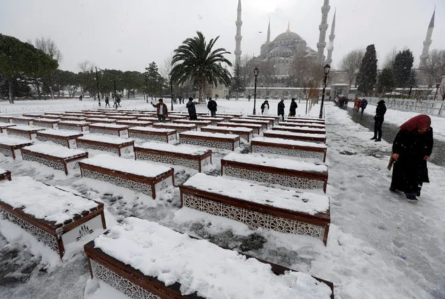 People stroll at the snow-covered Sultanahmet square in Istanbul, Turkey January 8, 2017. The Ottoman-era Sultanahmet mosque, known as the Blue mosque is seen in the background. (Photo by Murad Sezer/Reuters)