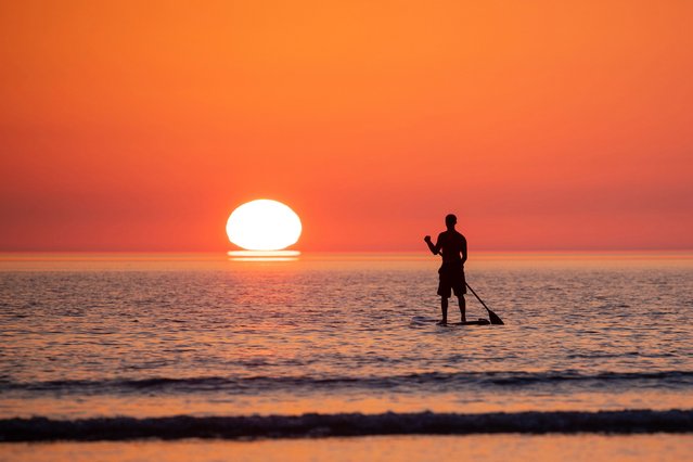 A stand up paddle boarder watches the sunset over the North Devon coast on July 20, 2021, as the heatwave continues across the UK. (Photo by Roy Riley/The Sun)