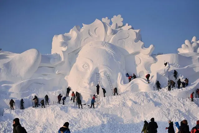 This photo taken on December 23, 2023 shows employees working on a snow sculpture in Harbin in China's northeastern Heilongjiang province. (Photo by AFP Photo/China Stringer Network)
