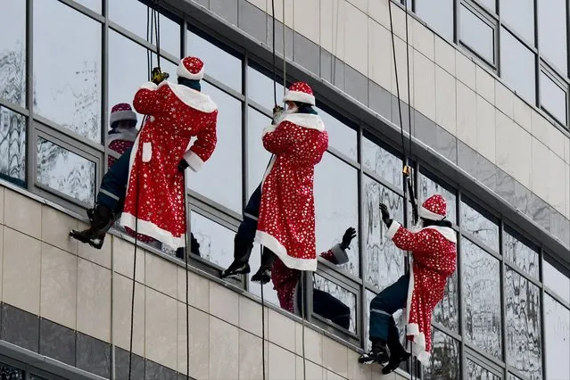 Russian rescuers dressed as Father Frost descend from the roof of the Almazov National Research Medical Center to greet seriously-ill children ahead of New Year and Orthodox Christmas celebrations in Saint Petersburg on December, 28 2023. (Photo by Olga Maltseva/AFP Photo)