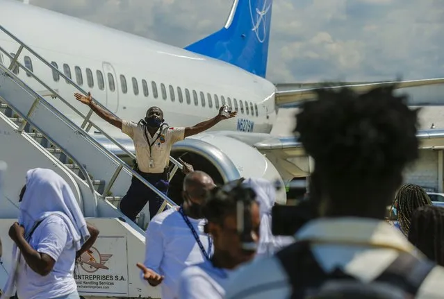 A police officer tries to block Haitians deported from the United States from boarding the same plane they were deported on, in an attempt to return to the United States, on the tarmac of the Toussaint Louverture airport, in Port-au-Prince, Haiti, Tuesday, September 21, 2021. (Photo by Joseph Odelyn/AP Photo)