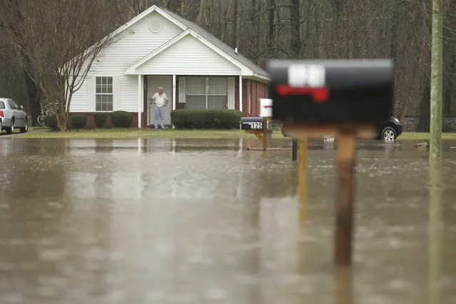 A homeowner can only watch from his front door as water levels rise near his house and flood the streets along Evergreen Drive in Saltillo, Mississippi Wednesday, February 20, 2019. Floodwaters covered roads on Wednesday in parts of eastern Mississippi and northern Alabama. (Photo by Thomas Wells/Northeast Mississippi Daily Journal via AP Photo)