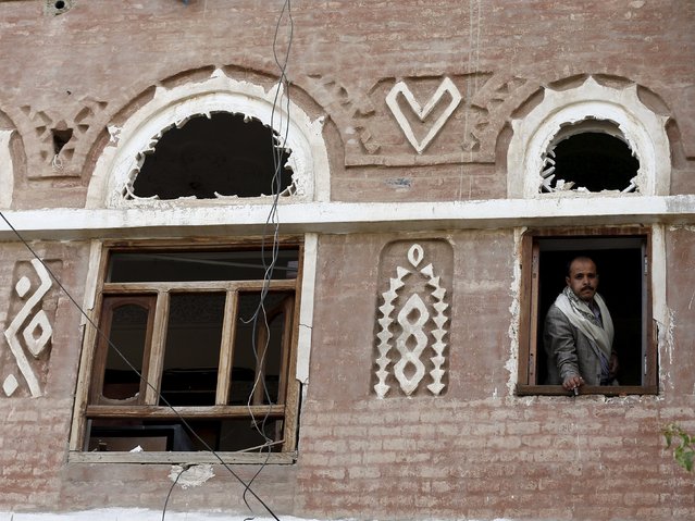 A man looks from a window of his house, damaged by an air strike, at a nearby house in Sanaa April 26, 2015. (Photo by Khaled Abdullah/Reuters)