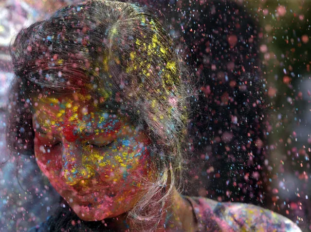 In this Thursday, March 21, 2019, file photo, revelers throw colored powder on a woman during celebrations marking Holi, the Hindu festival of colors, in Mumbai, India. (Photo by Rajanish Kakade/AP Photo)