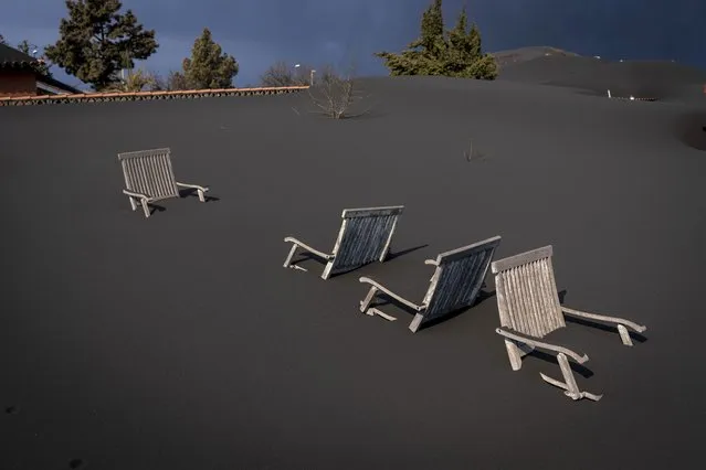 Ash covers chairs on the terrace of a house as volcano continues to erupt on this Canary island, Spain, Saturday, October 30, 2021. Scientists estimate the volcano also has ejected over 10,000 million cubic meters of ash. The ash is jettisoned thousands of meters into the sky, but the heaviest, thickest particles eventually give way to gravity. They accumulate into banks that slowly cover doors, pour into windows, make rooftops sag. (Photo by Emilio Morenatti/AP Photo)