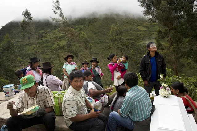 In this March 29, 2016 photo, people eat and visit during a burial for over 30 villagers killed more than two decades ago by Shining Path rebels in Ccano, a village in the Huanta area of Ayachcuo department, Peru. Officials exhumed the victims’ bones from an unmarked mass grave and returned the remains to the village in simple white caskets. (Photo by Rodrigo Abd/AP Photo)