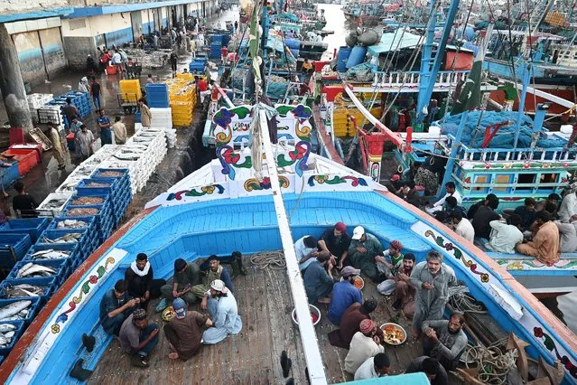 Fishermen break their fast on the decks of fishing boats at a harbor during the Islamic holy month of Ramadan in Karachi on March 20, 2024. (Photo by Rizwan Tabassum/AFP Photo)