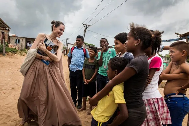 In this handout image provided by United Nations High Commission for Refugees, UNHCR Special Envoy Angelina Jolie speaks with children in Riohacha, Colombia, on June 7, 2019. Jolie visited the children, who had fled Venezuela, in Brisas del Norte, an informal settlement inhabited by Colombian refugees who have returned to their country as well as Venezuelans escaping a political and economic crisis back home. Over 4 million Venezuelans are now living in exile, with Colombia taking in the greatest share, even as it seeks to implement a peace deal ending five decades of conflict inside its own borders. (Photo by Andrew McConnell/UNHCR via Getty Images)
