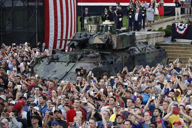 Audience members photograph a flyover in front of a Bradley Fighting Vehicle as President Donald Trump speaks during an Independence Day celebration in front of the Lincoln Memorial, Thursday, July 4, 2019, in Washington. (Photo by Alex Brandon/AP Photo)