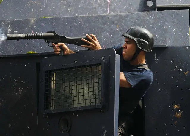 A Bolivarian National Police officer fires tear gas at anti-government protesters during clashes in Caracas, Venezuela, on April 1, 2014. Riot police prevented the protesters from reaching the assembly, where opposition lawmaker Maria Corina Machado was stripped of her parliamentary seat last week, after addressing the Organization of American States about the conditions of Venezuela. (Photo by Fernando Llano/Associated Press)