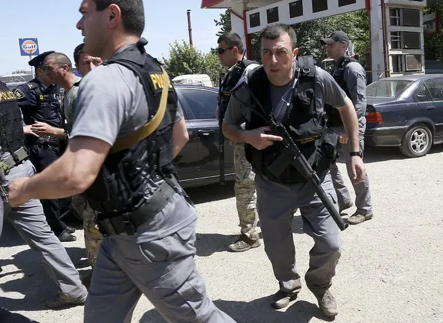 Armed policemen run after police killed a white tiger that had escaped from its enclosure during flooding, in Tbilisi, Georgia, June 17, 2015. Tigers, lions, bears and wolves were among more than 30 animals that escaped from a Georgian zoo and onto the streets of the capital Tbilisi on Sunday during floods that killed at least 12 people. REUTERS/David Mdzinarishvili