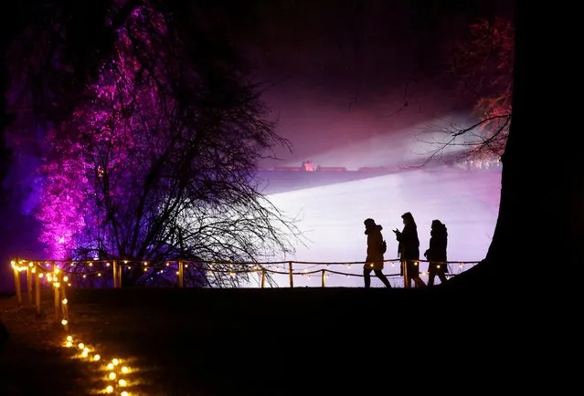 People walk through Nature Illuminated experience depicting immersive and sensorial lights and sounds effects on the theme of the four seasons in the park of the Groot-Bijgaarden Castle, near Brussels, Belgium on January 27, 2022. (Photo by Yves Herman/Reuters)