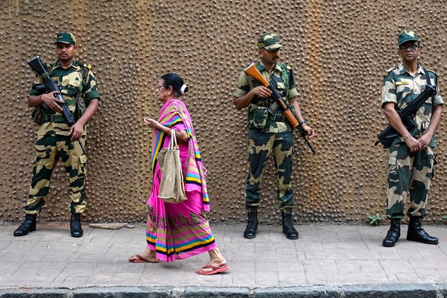A woman walks past Indian Border Security Force (BSF) soldiers outside the polling station during the fifth phase of voting in India's general election, in Mumbai on May 20, 2024. India's election is conducted in seven phases over six weeks to ease the immense logistical burden of staging the democratic exercise in the world's most populous country. (Photo by Punit Paranjpe/AFP Photo)