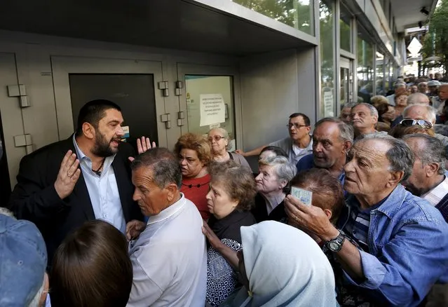 A bank manager tries to explain the situation to hundreds of pensioners queuing outside a National Bank branch in Athens, Greece, July 1, 2015. About one thousand Bank branches around Greece opened on Wednesday to allow pensioners to receive a small part of their benefits. (Photo by Yannis Behrakis/Reuters)