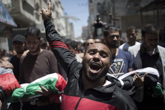 A Palestinian man chants angry slogans during the funeral of three children who were killed in a fire caused by candle in the Shati refugee camp in Gaza City, Saturday, May. 7, 2016. Three Palestinian children have been killed in a Gaza house fire started by a candle, sparking internal finger-pointing over the coastal territory's lingering power crisis. (Photo by Khalil Hamra/AP Photo)
