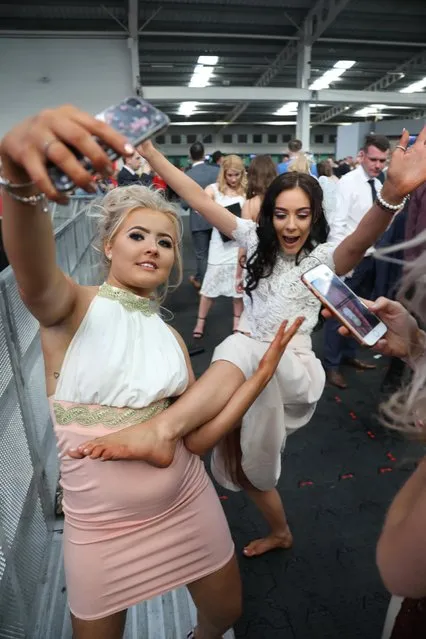 Two ladies attempt to take a quick selfie during the Grand National Festival at Aintree Racecourse on April 7, 2017 in Liverpool, England. (Photo by WENN)