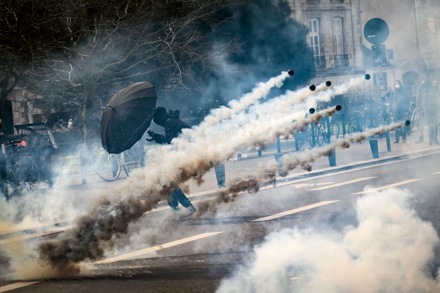 A black bloc protestor holds an umbrella to protect from teargas during a demonstration on the 8th day of strikes and protests across the country against the government's proposed pensions overhaul, in Nantes, on March 15, 2023. France faces another day of strikes over highly contested pension reforms which President appears on the verge of pushing through despite months of protests. As the legislation enters the final stretch in parliament, trade unions are set to make another attempt to pressure the government and lawmakers into rejecting the proposed hike in the retirement age to 64. (Photo by Loic Venance/AFP Photo)